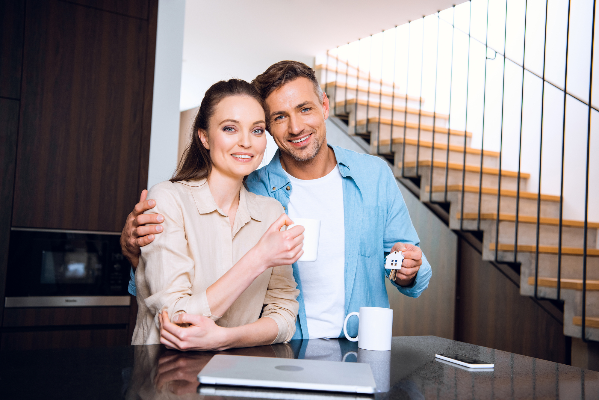 Smiling couple at a table with papaerwork in frontt of them.